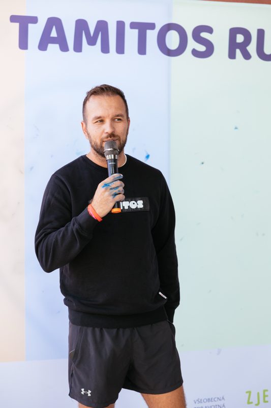 The host with a microphone at the photo wall